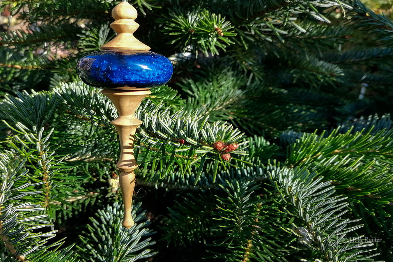 Handgemaakt via houtdraaien, ornament voor kerst van buxus hout met een bal van epoxy kunst glas in blauw met goud. deze hant in een kerstboom. 