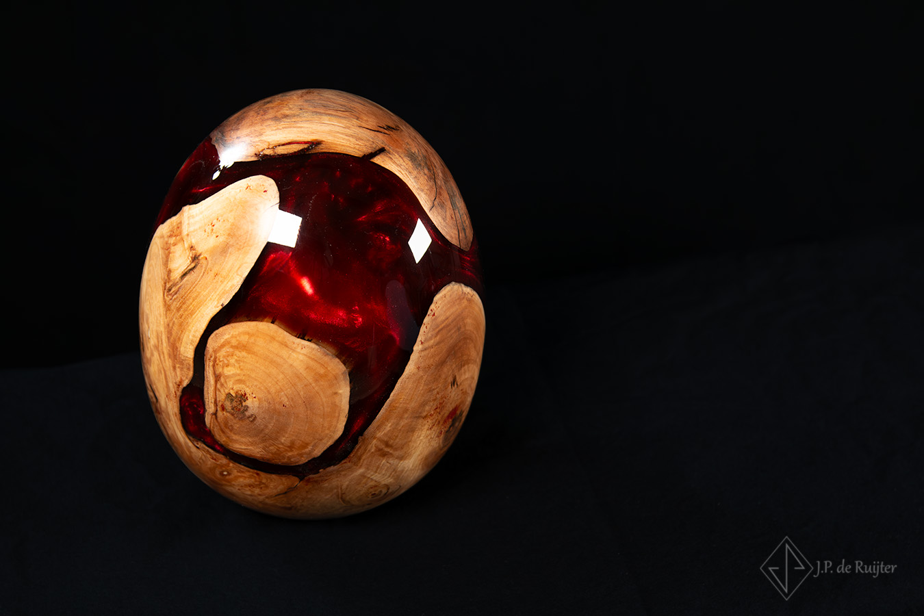 Bovenaanzicht van een urne in eivorm van hout met epoxy in rood. Uniek ontwerp.