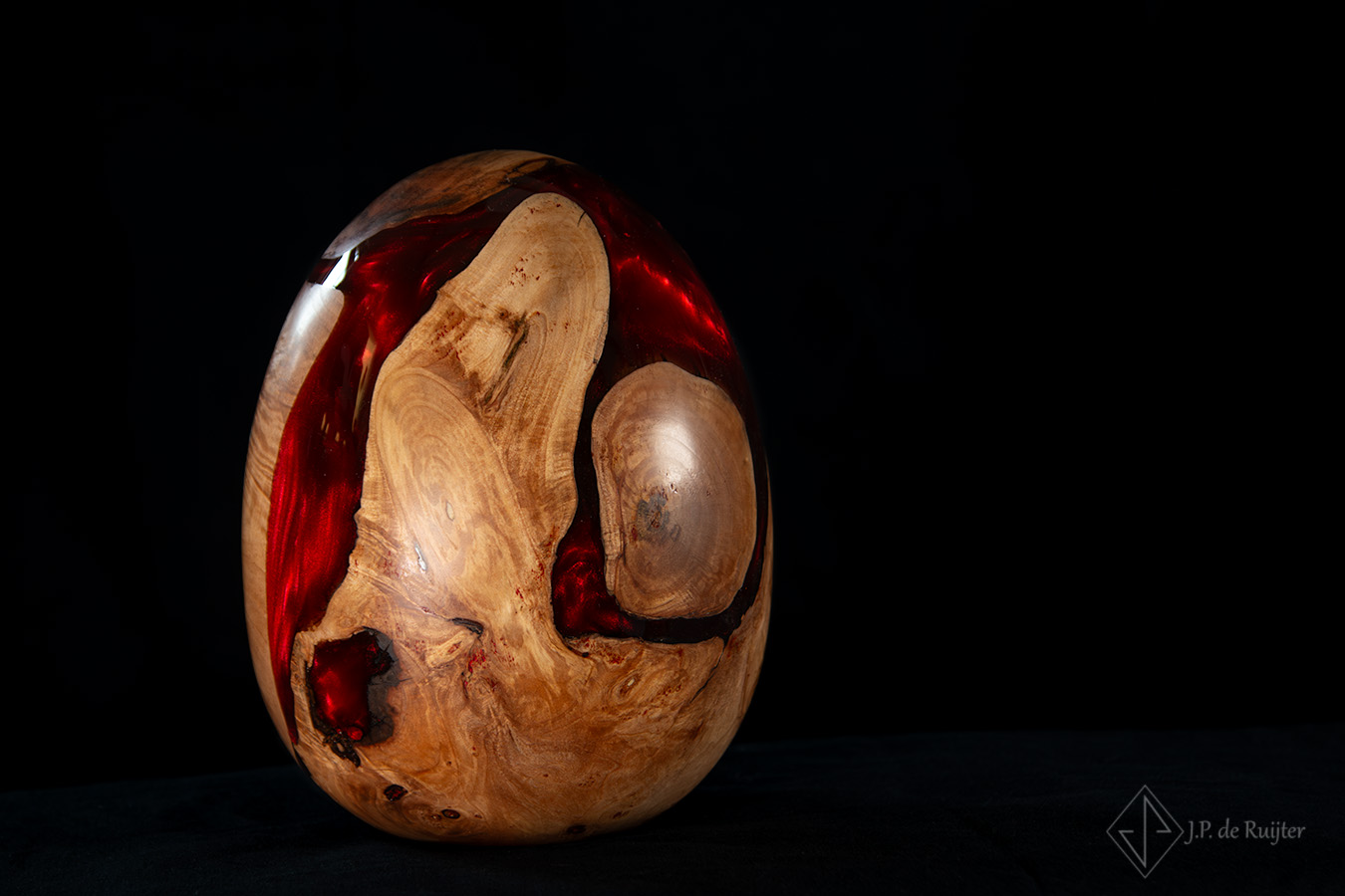 As urn in eivorm van hout met epoxy in rood.