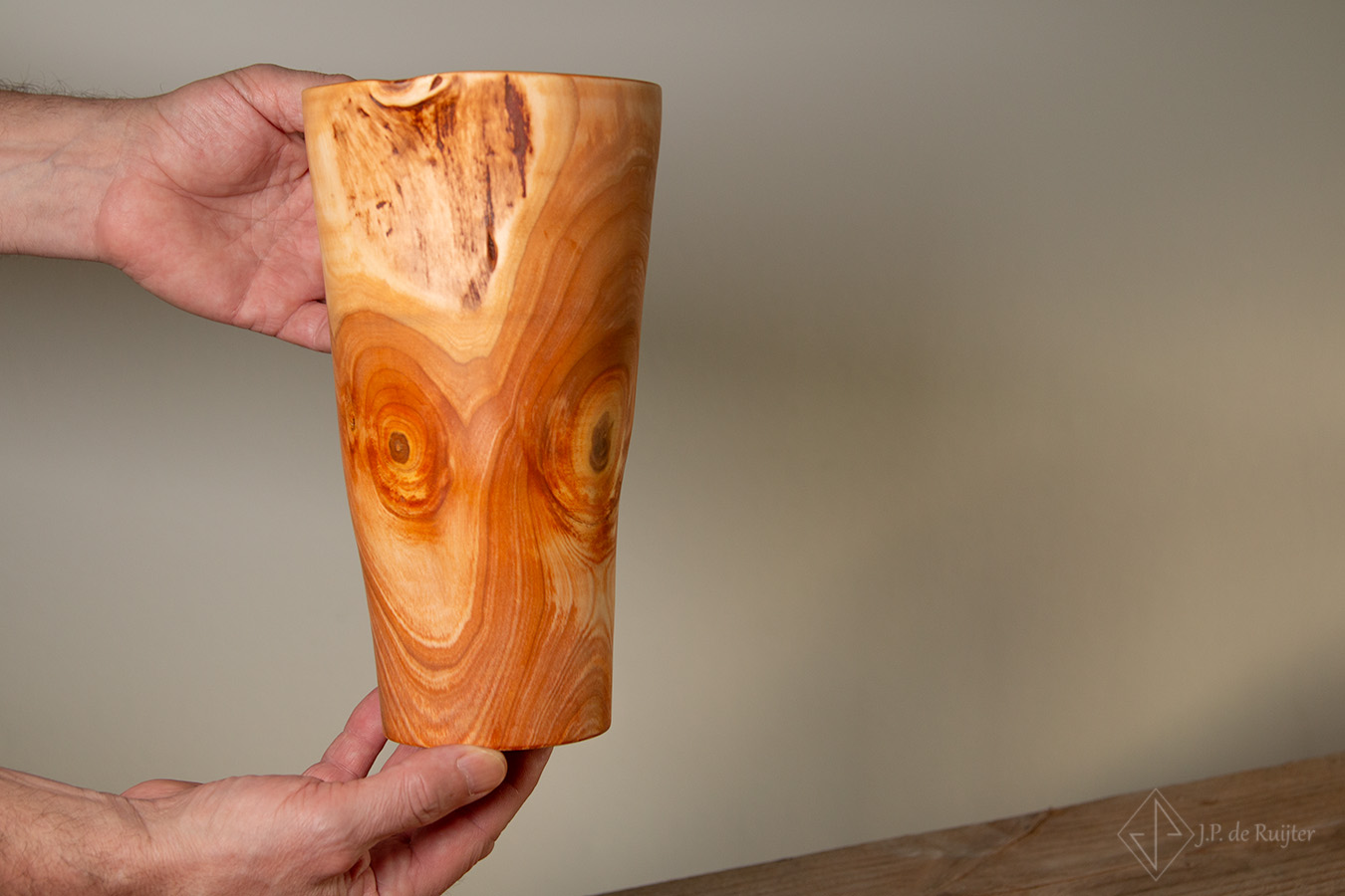 Vaas van kersen hout, met een mooie beweging in de vaas door natuurlijke vervorming. Vaas getoond in de handen zodat de afmeting beter te zien is. 